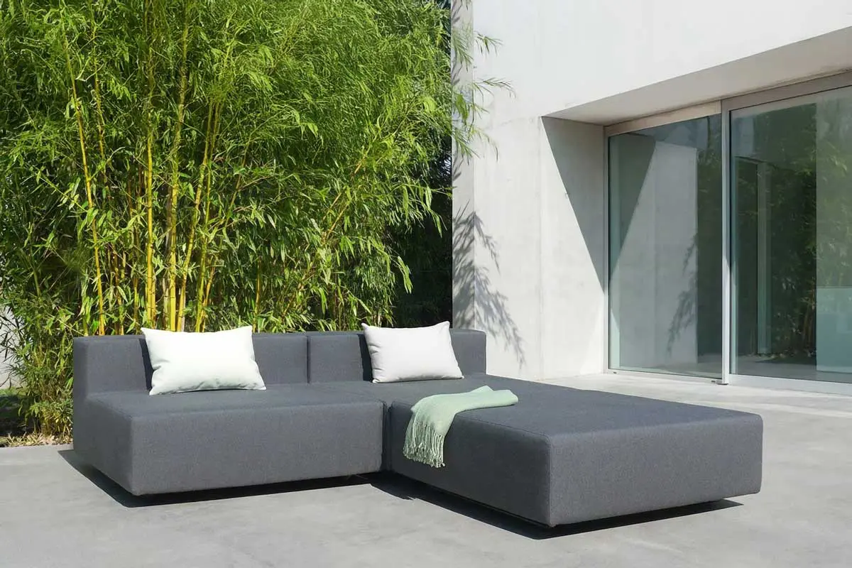 Set aus drei LOOP Elementen mit Kissen und Decke auf Steinterrasse im Grünen.
